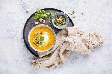 A bowl of fragrant homemade cream of pumpkin soup decorated with pumpkin seeds and fresh coriander...