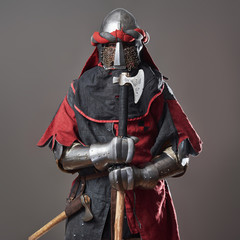 Medieval knight on grey background. Portrait of brutal dirty face warrior with chain mail armour...