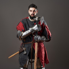 Medieval knight on grey background. Portrait of brutal dirty face warrior with chain mail armour...