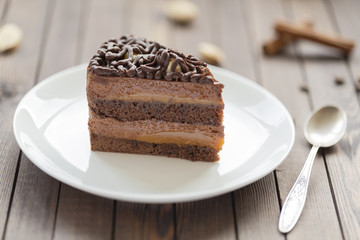Dessert souffle with chocolate sauce and nuts on a white plate, on a wooden table.