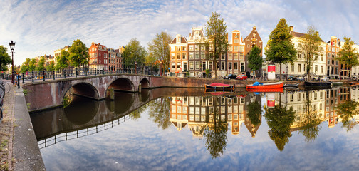 Fototapeta premium Piękny zachód słońca w Amsterdamie. Typowe stare holenderskie domy na moście i kanałach wiosną, Holandia