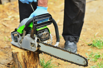 A man in blue working gloves launches a chainsaw