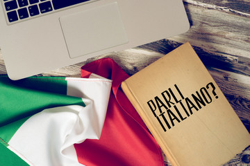 Ein Computer, Flagge von Italien und Buch mit dem Titel Sprechen Sie italienisch