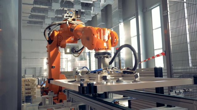 Automated robotic arm works in a factory floor.