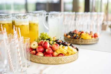 Fresh Fruit platter buffet at business or wedding event venue. Self service or all you can eat - cherries, nectarine, grapes and pineapple. Table with cold drink and snacks and tableware