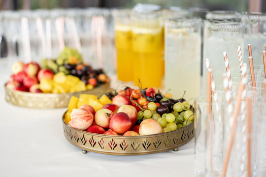Fresh Fruit platter buffet at business or wedding event venue. Self service or all you can eat - cherries, nectarine, grapes and pineapple. Table with cold drink and snacks and tableware