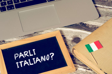 Ein Computer, Flagge von Italien und eine Kreidetafel mit der Frage Sprechen Sie italienisch