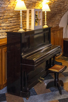 old piano with lamps near a brick wall in a vintage cafe