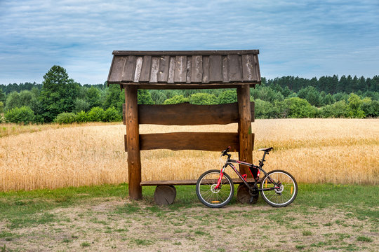 a wooden gazebo bench with bike in a wheat field