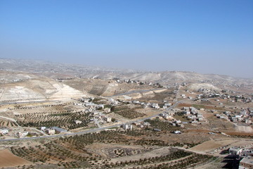 Fototapeta na wymiar The landscape of the Israeli valleys with small settlements at the foot of the hills in the background of a cloudy blue sky.