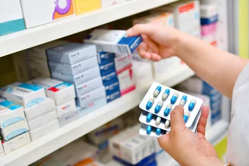 Papier Peint photo Pharmacie Pharmacien tenant une boîte à médicaments et un pack de capsules dans une pharmacie de pharmacie.