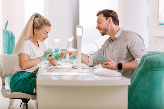 Talking to master. Attractive metrosexual feeling relaxed and contended while talking to his favorite nail master