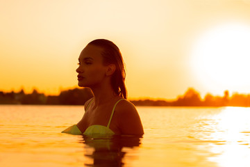 Sexual young lady in the sea at warm sunset