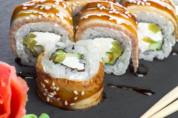 Japanese restaurant, sushi roll on black slate plate.