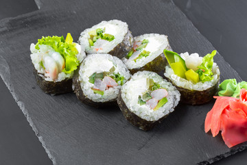 Japanese restaurant, sushi roll on black slate plate.