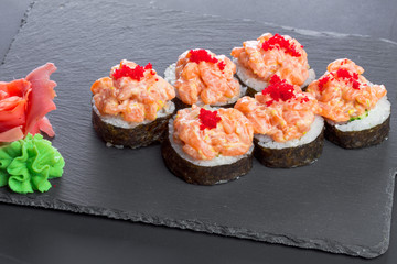 Japanese restaurant, sushi roll on black slate plate.