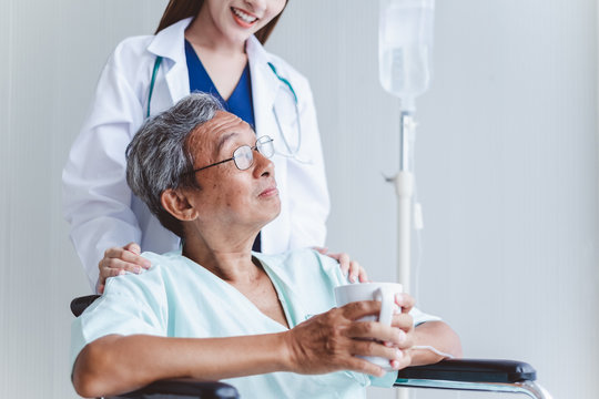 Asian Doctor Woman Encourage Disabled Old Man Patient Sitting On Wheelchair At Hospital, Asian Medical Concept