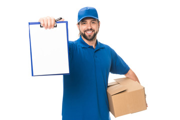 handsome happy young delivery man holding cardboard box and blank clipboard isolated on white