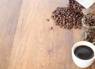 A cup of coffee and beans on wooden table background