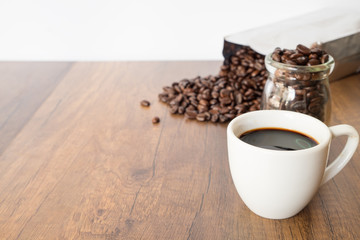 A cup of coffee and beans on wooden table background