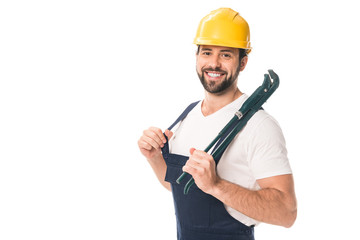 handsome happy workman holding adjustable wrench and smiling at camera isolated on white