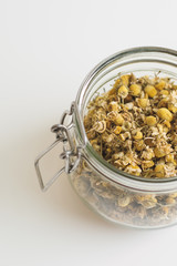 Dried chamomile tea in a jar, vertical photo