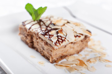 Almond cake. Piece of Cake with leaf mint on a Plate. Sweet food. Sweet dessert. Food background. Close up.