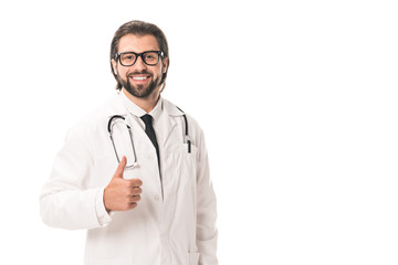Fototapeta premium handsome doctor in eyeglasses and white coat showing thumb up and smiling at camera isolated on white