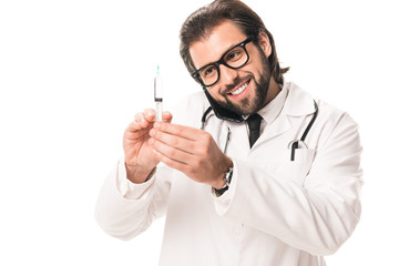 happy doctor holding syringe and talking by smartphone isolated on white