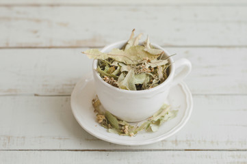 Cup with dried lime flowers on wooden table. Healthy herbal tea
