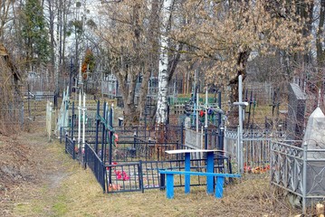An old cemetery with crosses and fences in dry grass and trees
