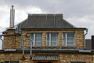 facade of an old brick house with three windows on a sky background