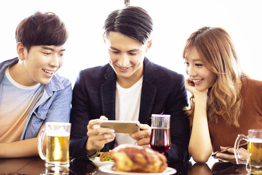 young friends watching the smartphone at restaurant
