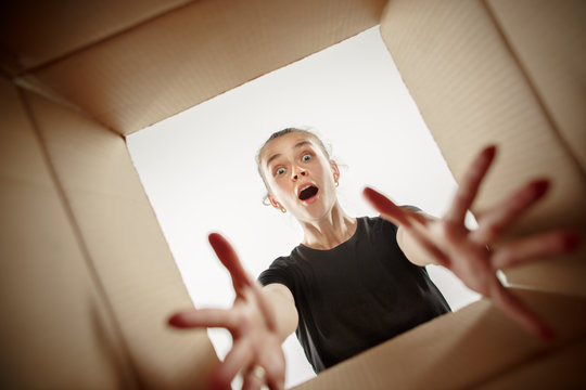 The surprised woman opening box and looking inside. The package, delivery, surprise, gift, lifestyle concept. Human emotions concepts