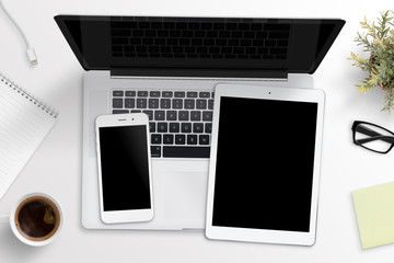 Smart phone and tablet mockup on laptop keyboard. Office desk concept. Top view.