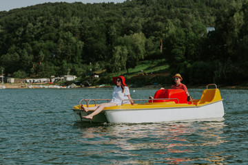 Fototapeta na wymiar Couple in love enjoying boating in the lake. Portrait of young man and woman pedal boating on the river.