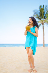 Young beautiful asian woman is drinking coconut juice on the beach