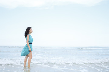 Fototapeta na wymiar Young beautiful asian woman is walking along the beach