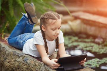 Girl with digital tablet in botanical garden