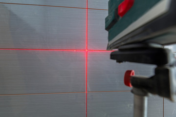 Installation of new tiles on the wall using a laser level
