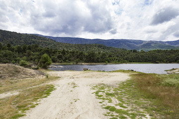 view of a landscape of a lake surrounded by mountains and trees on a cloudy day
