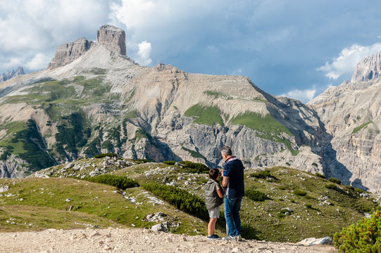 Dad teaching his son to take a picture in the Italian Alps, near the Tre Cime, in the Dolomites, on a summer afternoon.