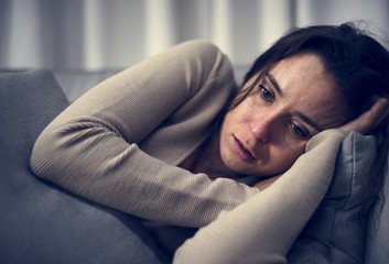 Depressed woman lying on the bed - obrazy, fototapety, plakaty