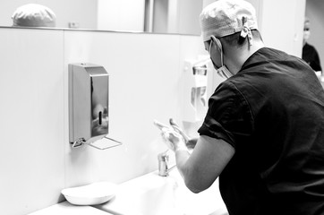 The doctor washes his hands in front of the mirror before the operation.

