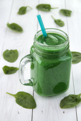 Green smoothie superfood in mason jar , made from spinach , cucmber and another vegetables on white wooden table , vertical