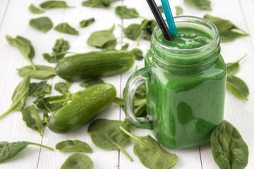 Green smoothie superfood in mason jar , made from spinach , cucmber and another vegetables on white wooden table