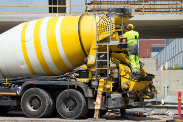 Construction site worker washing concrete truck