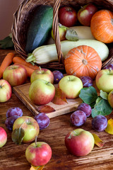 Fresh, juicy apples on a wooden table. Vegetables in the basket. Autumn harvest.