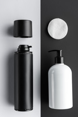 top view of bottles of cream and cosmetic pads on black and white surface, beauty concept
