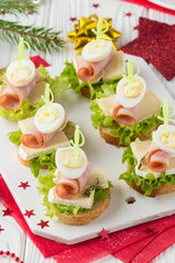 Christmas canapes on bread with brie or Camembert cheese, ham and boiled quail egg. Beautiful presentation on the festive new year's table. Delicious starter